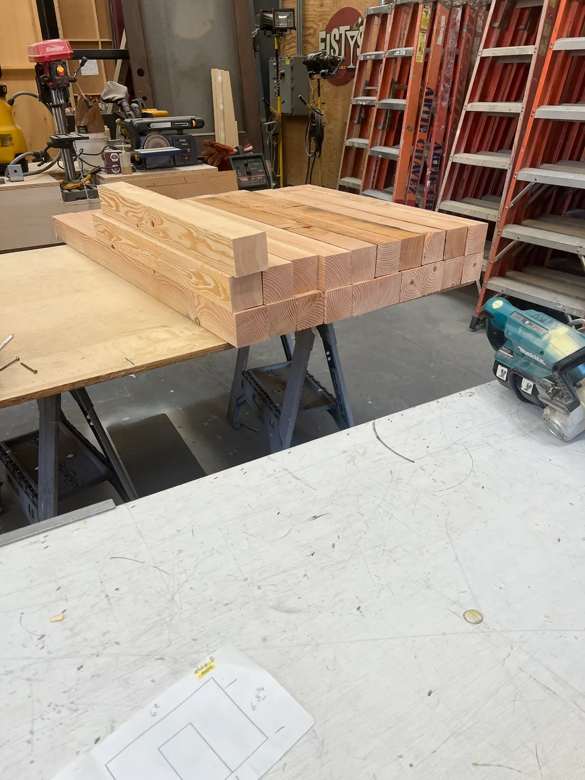 Freshly cut 4×4 bench legs stacked on sawhorses in the shop