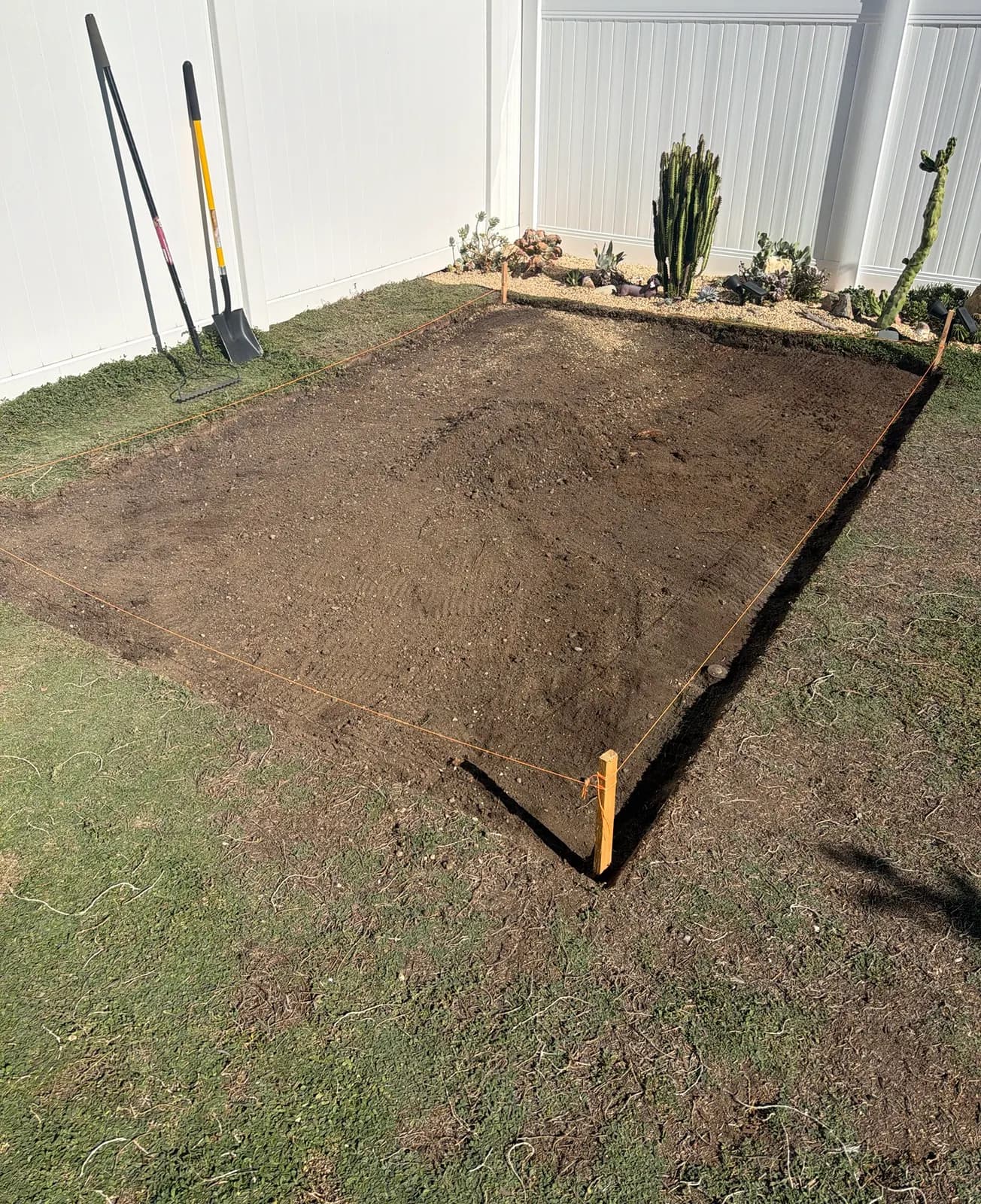 The pad cleared down to bare soil inside the string lines