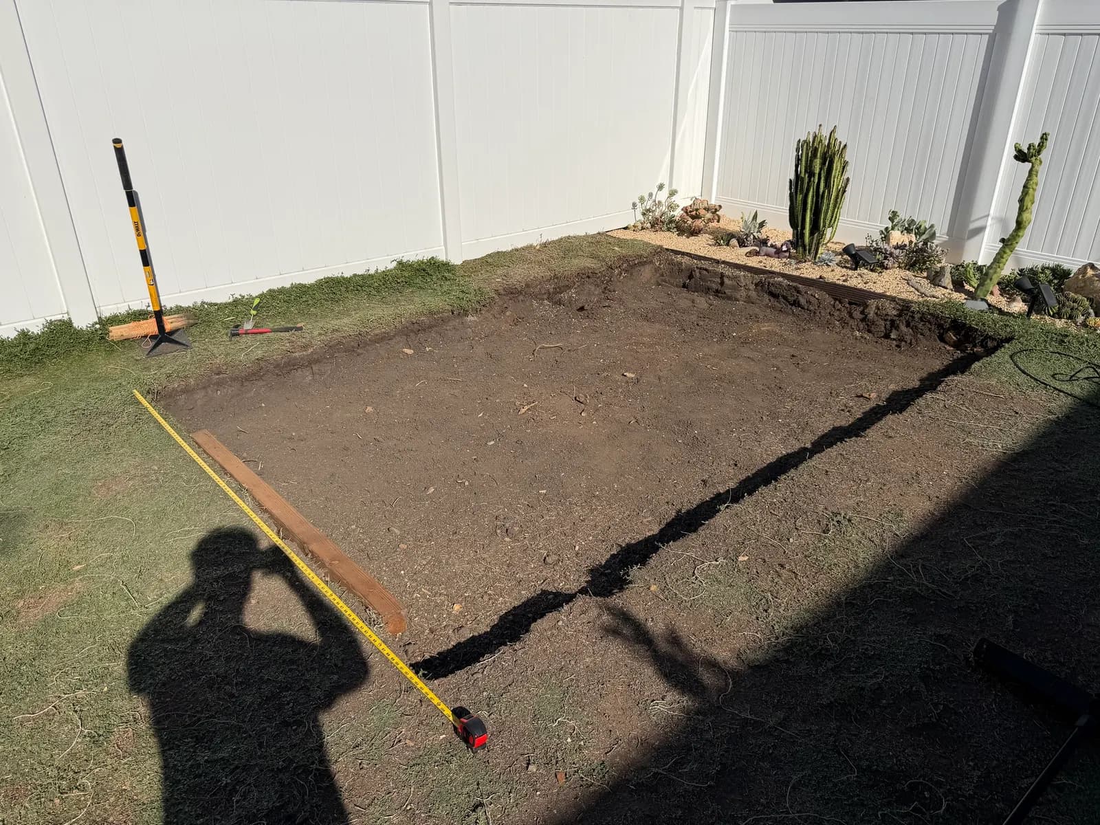 The excavated pad measured out with a tape, a timber laid along the edge